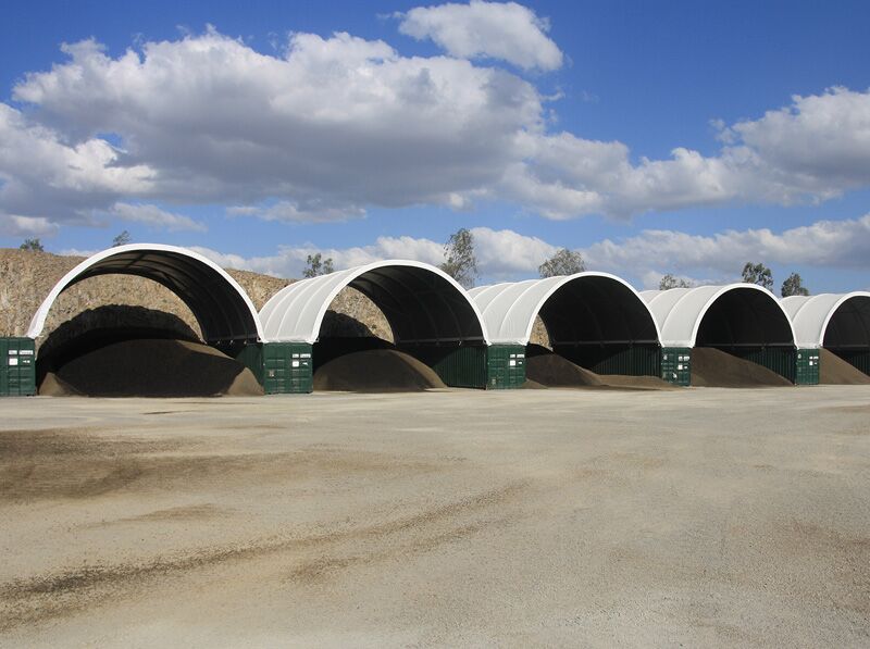Row of Fabric Shelters with Bulk Storage Multiple container-mounted fabric shelters used for bulk material storage in an open yard.