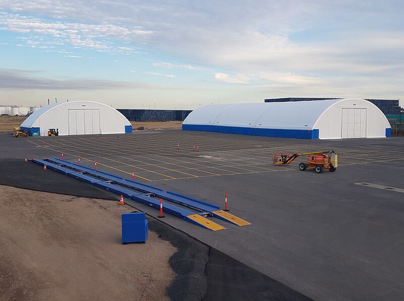 arge Fabric Shelters in Yard Two large fabric shelters in an open yard, used for industrial or storage purposes with clear and spacious surroundings.